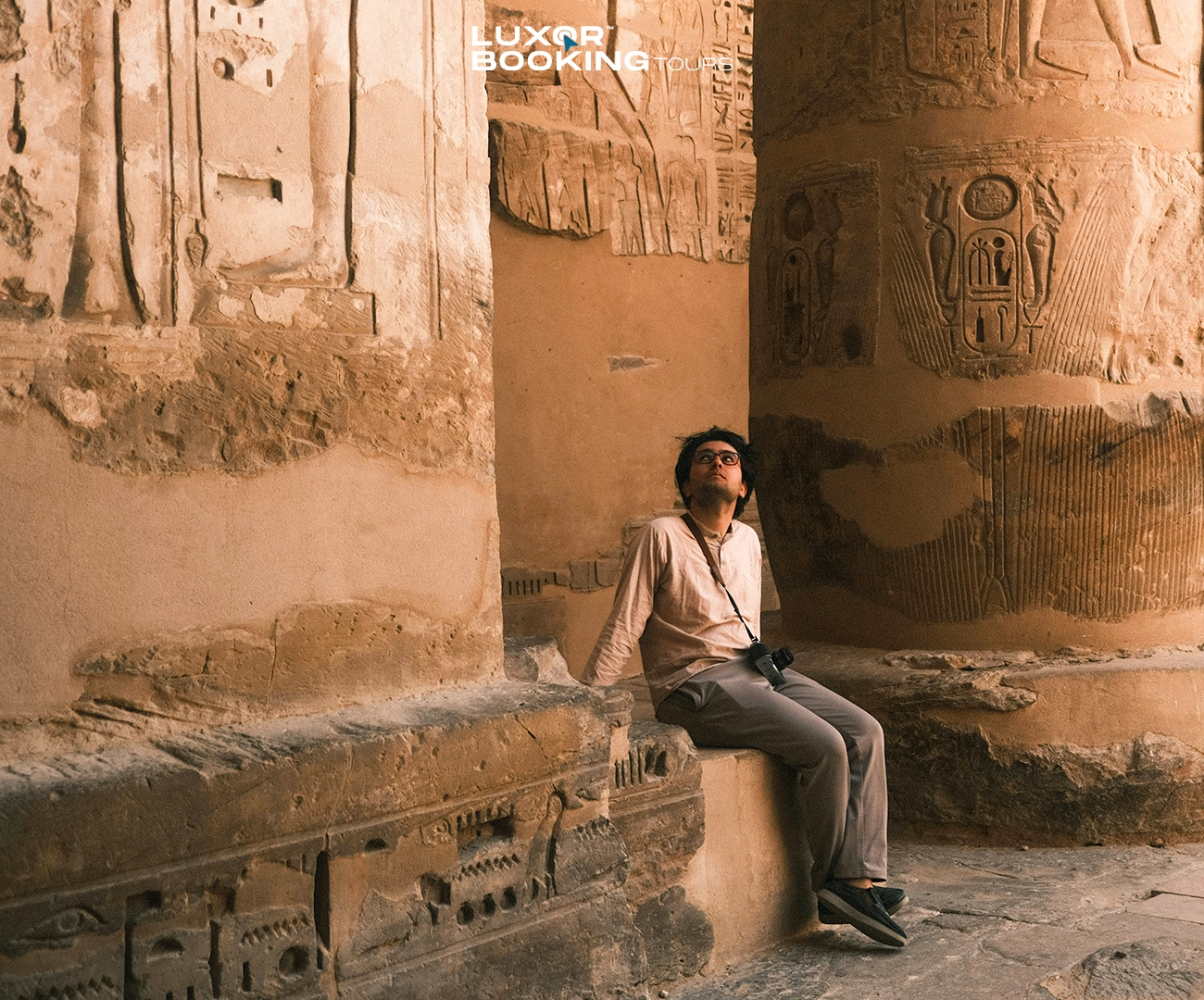 tourist resting in shade at luxor temple after walking in heat